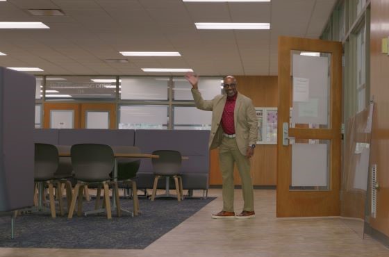 Dean Jackson smiling and waving in the main lobby of Erickson Hall