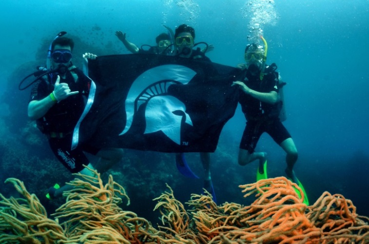 Students underwater with the Spartan flag
