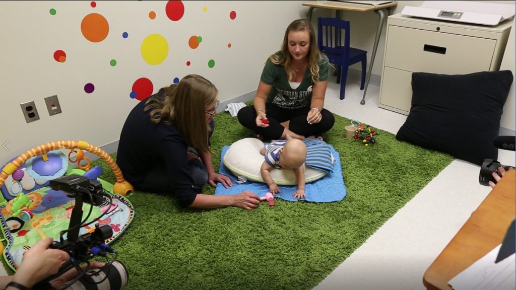 MSU scholar plays on the floor during a session of tummy time with an infant