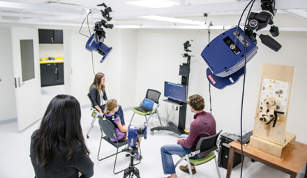 Mei-Hua Lee and two research assistants watch as 9-year-old Kayla Michael (center) performs a video game-like motion coordination challenge while wearing wireless sensors on her shoulders.