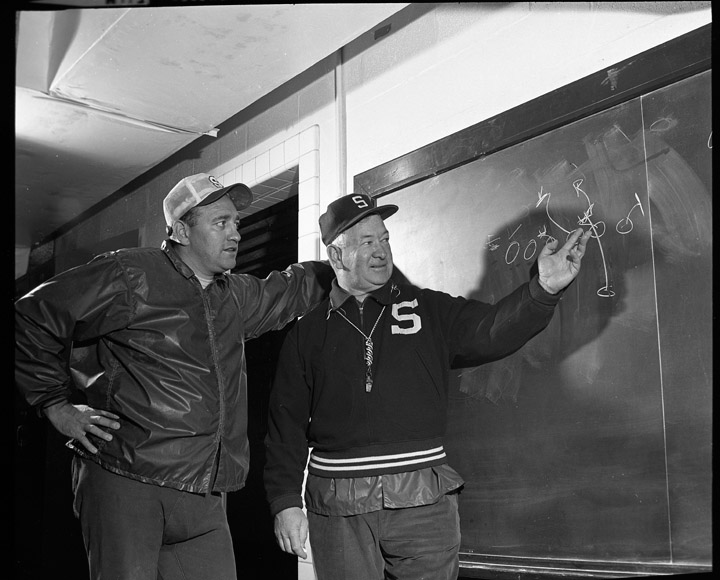 Henry "Hank" Bullough (left) looks over the shoulder of MSU head football coach Duffy Dougherty in 1968. Photo courtesy of University Archives.