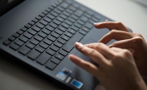 Hands type on a laptop