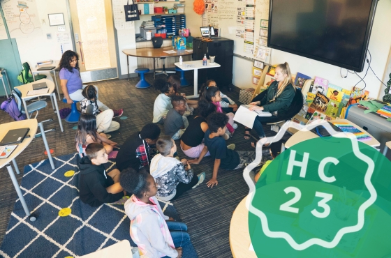 Spartan Educator reads to a classroom; MSU Homecoming logo in the loweer right corner