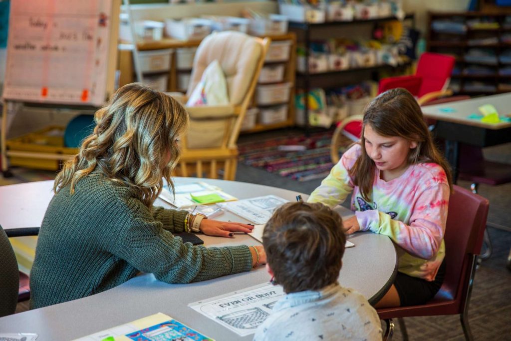 Lindsay working with a group of students a table.