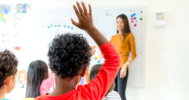 Student with hand up for answer question of teacher in classroom