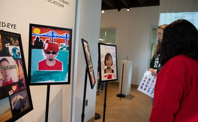 Students examine art at the "Do You Have Anything to Declare?" photo exhibit.