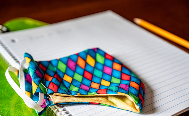 Stock photo from Getty: Colorful diamond patterned mask on spiral notebook with yellow no.2 pencil.