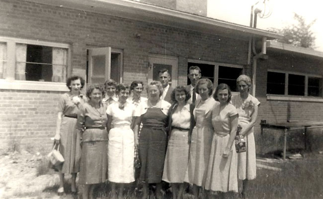 Undated black and white group photo including Phyllis Hiller in front of Elmwood Elementary School. 