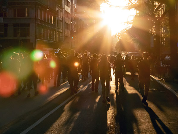 Stock image Crowd of people walking down the street into the bright light of sunset in New York City NYC, from Getty. 