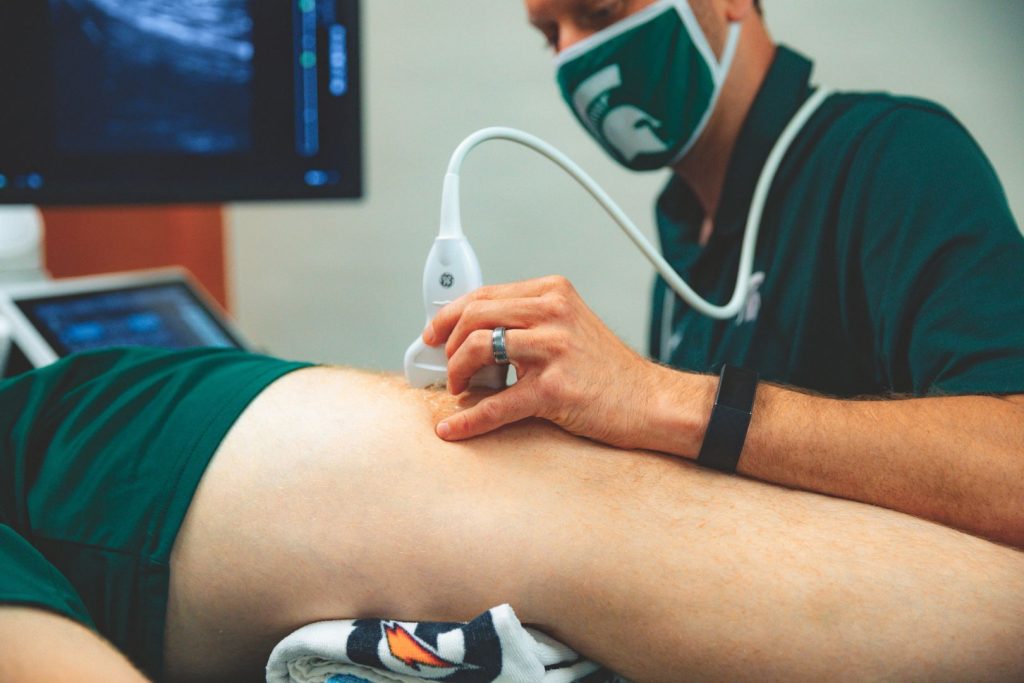Assistant Professor Matt Harkey performs ultrasound on the knee of an injured athlete.