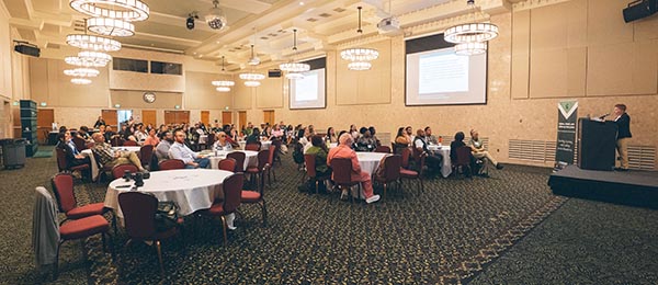 speaker at podium presenting to people sitting at tables