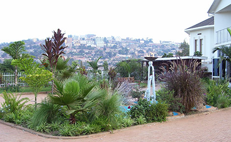 Kigali Genocide Memorial (a courtyard with plants), and Kigali, Rwanda in the background. 