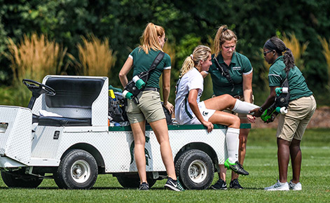 Spartan athletic trainers help an injured player on the field. 