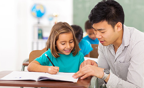 A teacher helps a preschooler with classwork. 