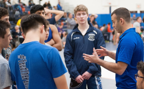 A coach talks to high school athletes during a meet. 