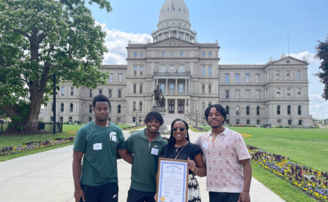 Jackson, pictured with her three sons, two of whom are Spartans, pose in front of the Michigan State Capitol with the Michigan Teacher of the Year award.