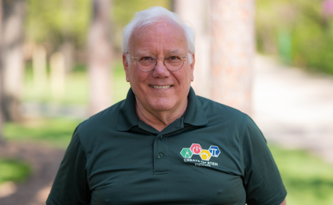 Professional headshot of Joseph Krajcik. He is wearing a green shirt and standing outdoors. 