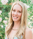 Trisha Easley headshot. Trisha stands outdoors. Trisha wears a light blue top and a silver necklace. Trisha's blonde hair is long and falls past the shoulders. 